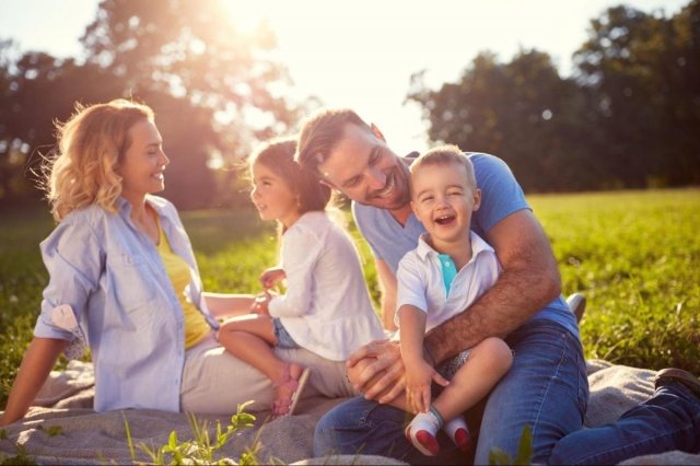 Family unplugging routine outdoors: parents and children enjoying screen‑free connection and nature.