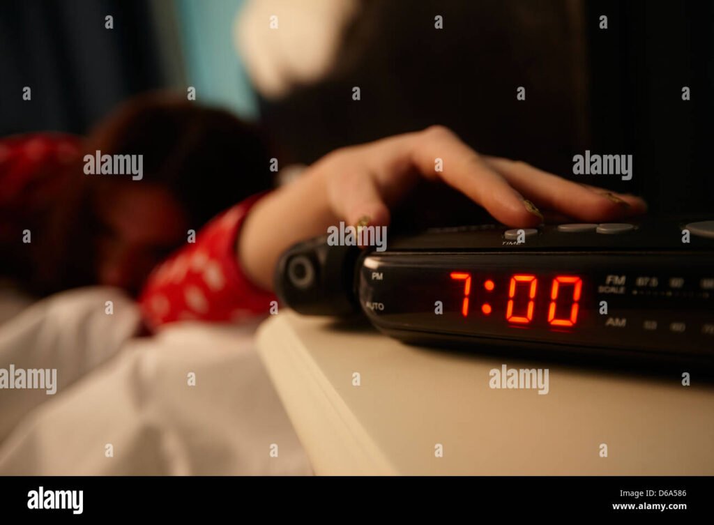 A close-up of a hand pressing an old-fashioned alarm clock button, symbolizing the start of a mindful, tech-free morning unplugging rituals .