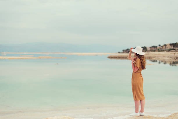 Stylish girl standing by Dead Sea, embracing freedom and digital detox
