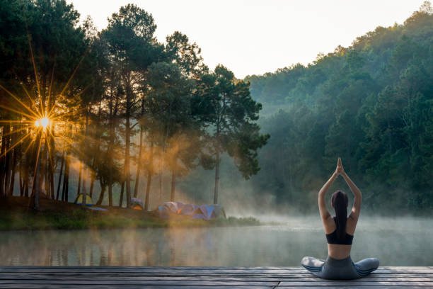 Morning vs Evening Unplugged Routines: What’s Best for Your Mind and Body? Woman practicing yoga at sunrise by a tranquil forest lake, symbolizing a peaceful and mindful start to the day.Unplugged Routine