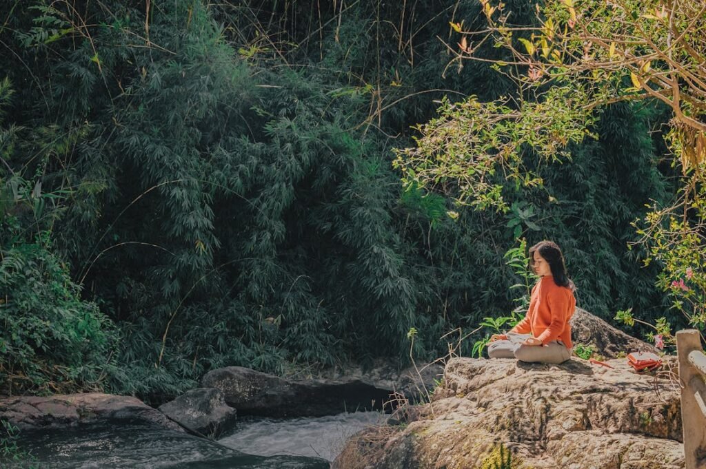 Woman sitting peacefully on a wooden bench in nature, embracing stillness and mindful rest.