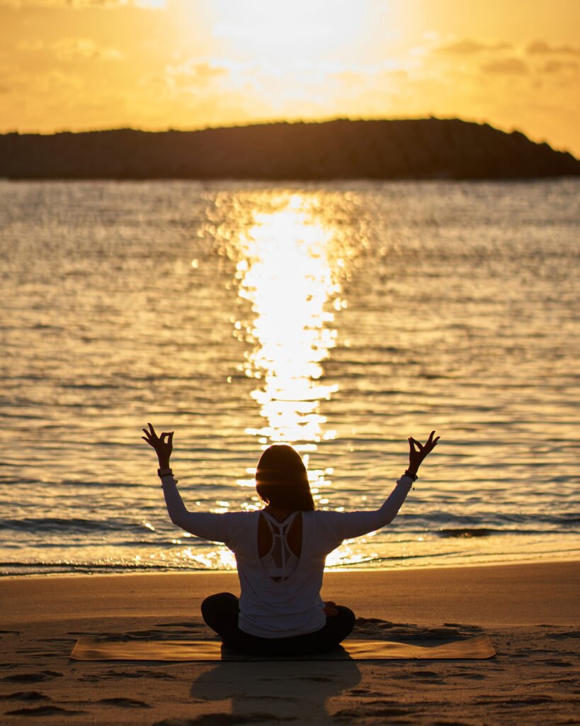 A woman practicing meditation on a wooden deck overlooking a tranquil lake at sunrise, symbolizing peace, mindfulness, and digital detox in nature.