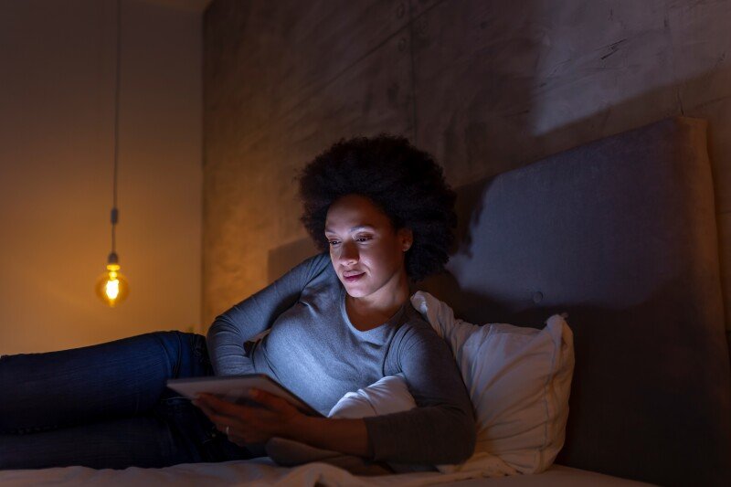 Dim bedside scene of reading in bed, ideal for representing the unplug‑before‑sleep habit that supports relaxation and sleep readiness