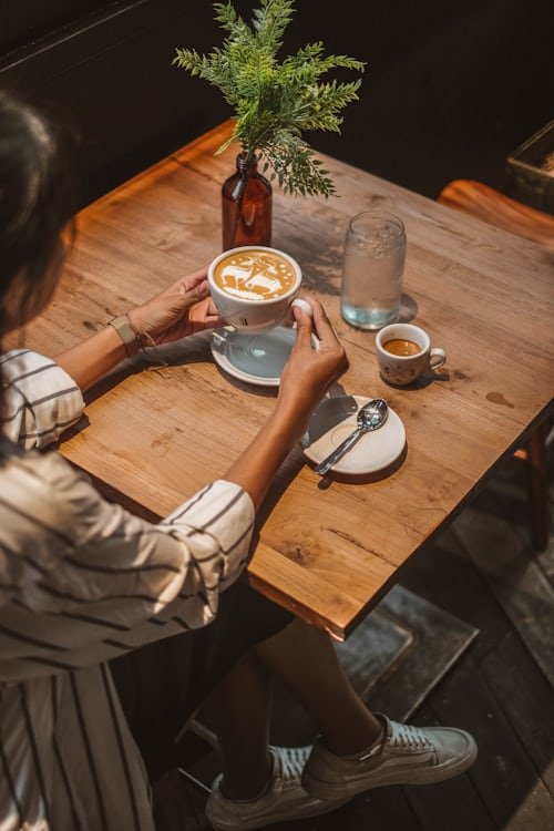How to Start a 7‑Day Digital Detox Challenge Woman relaxing in bed with a book and a cup of coffee, enjoying a peaceful morning without digital distractions during a digital detox.
