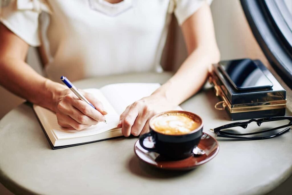 Morning sunlight shines on a journal and coffee cup, symbolizing a peaceful moment of journaling for unplugging and reconnecting with yourself in a distracted world.