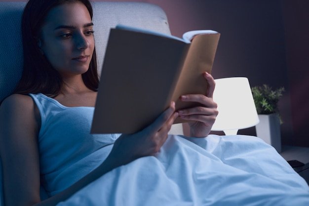 Close-up of a book being read in bed with gentle lighting, illustrating an unplug-before-sleep bedtime ritual.