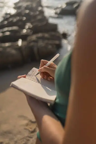 Blog A person practicing mindfulness exercises by writing in a journal on a peaceful beach.