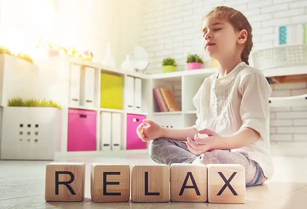 Blog "A child practicing a mindfulness meditation exercise to relax in her room, demonstrating a simple wellness activity for kids."