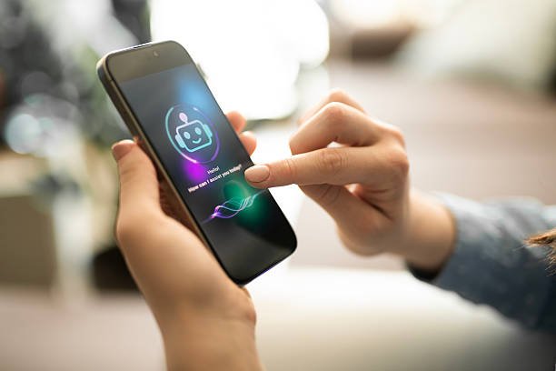 A woman's hands holding a smartphone, with her finger touching the screen which displays a friendly AI chatbot for a mental wellness apps asking, "Hello! How can I assist you today?".