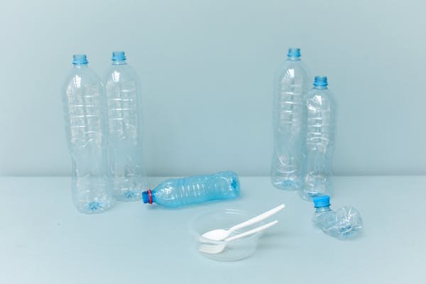 7 Powerful Ways to Track Your Carbon Footprint at Home and Make a Real Impact "Plastic bottles and disposable utensils on a stripped-down tabletop, illustrating waste and carbon footprint impact"