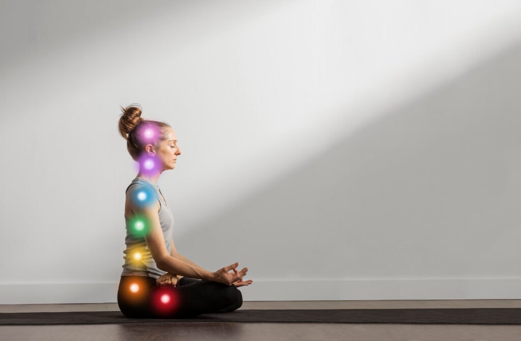 Blog Side view of a woman with her eyes closed engaged in a deep Body Scan Meditation, with seven colorful, glowing chakras illustrating a focus on the body's energy centers