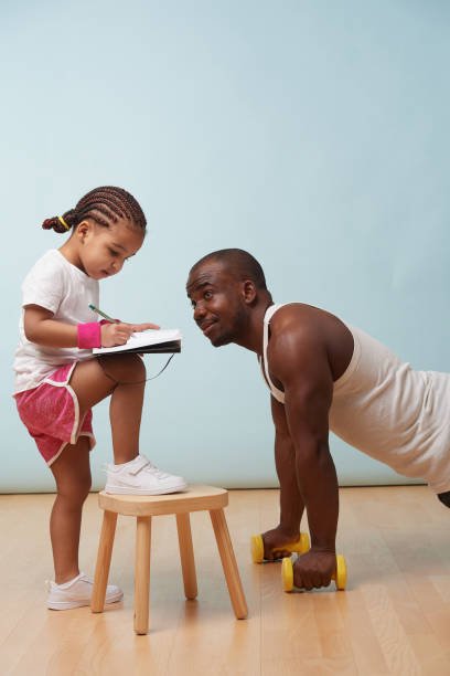 Scheduling Workouts with Family Commitments: 12 Secrets to a Guilt-Free Routine A cheerful little daughter "fitness training" her father, symbolizing the fun and interactive side of scheduling workouts with family commitments.