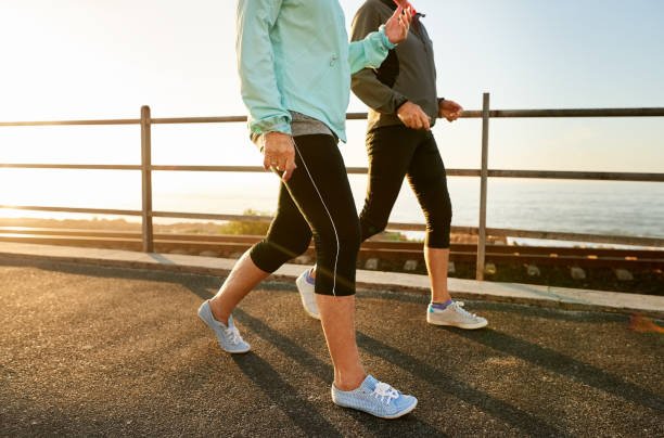 Close-up of a woman's sneakers on pavement as she takes the first step of her walk, a key part of a healthy morning fitness routine.